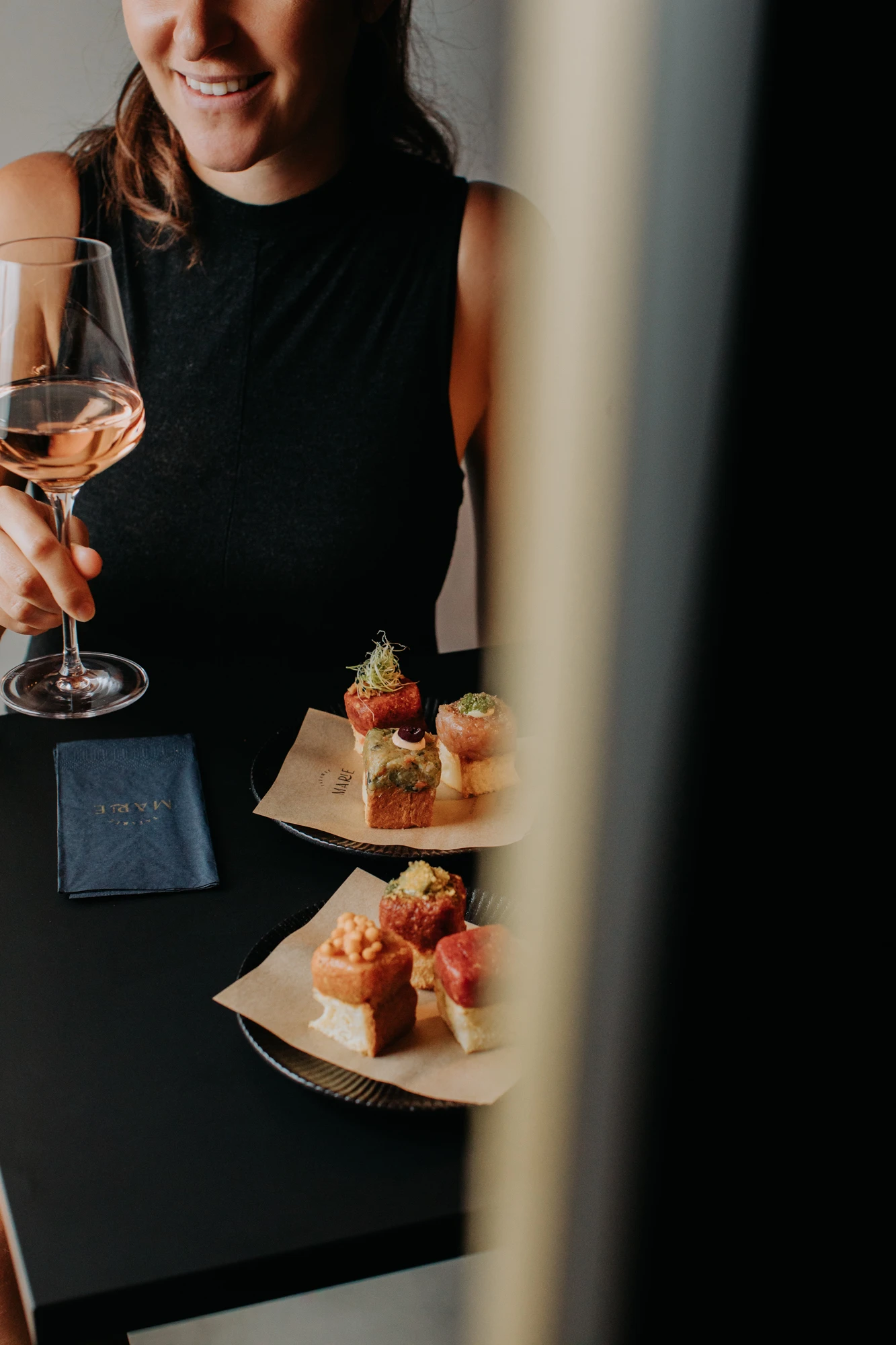 Frau genießt Roséwein und Häppchen in einem Restaurant oder Bar.